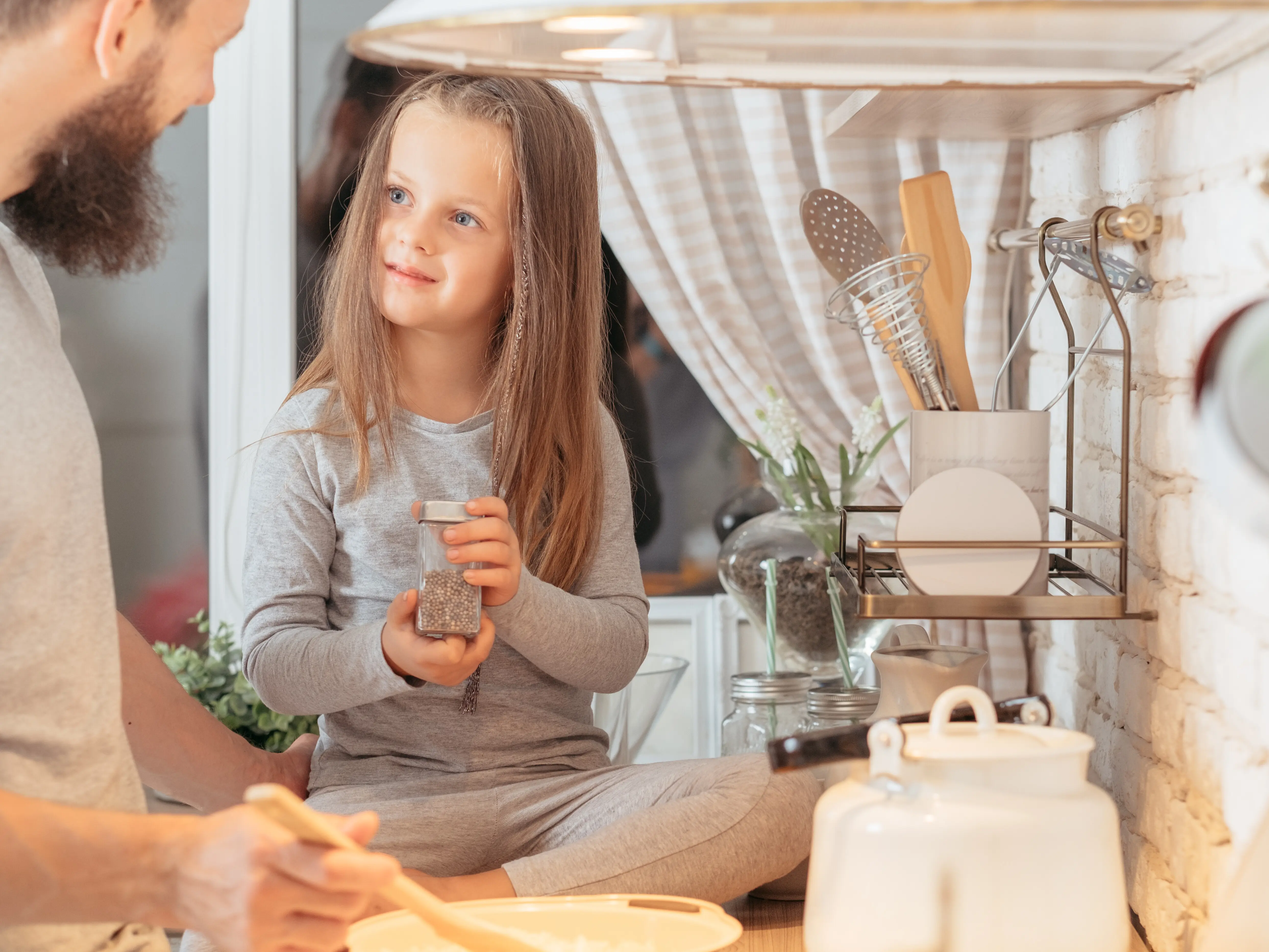 Glückliche Familie: Ein Vater bringt seiner kleinen Tochter bei, wie man kocht; das neugierige Mädchen hört aufmerksam zu.
